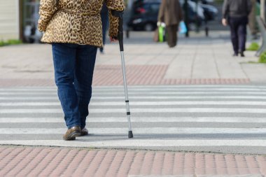 kadın bir yaya geçidi, bir koltuk değneği ile arka görünüm