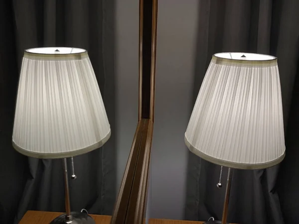 table lamp with lampshade on the table in front of a mirror