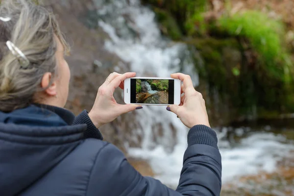 Mulher fotografar uma bela cachoeira com um smartphone — Fotografia de Stock
