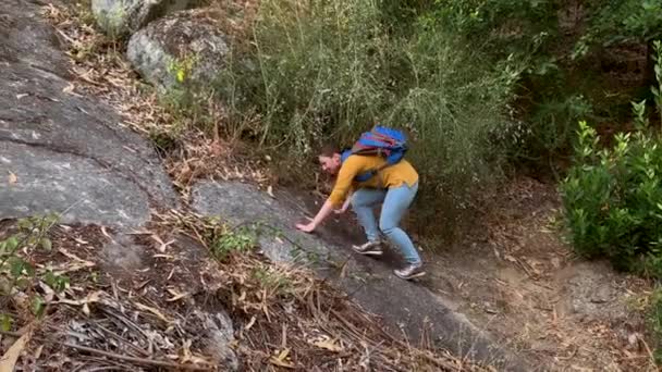 年轻女子游客背着背包独自徒步攀登森林中的岩石 — 图库视频影像