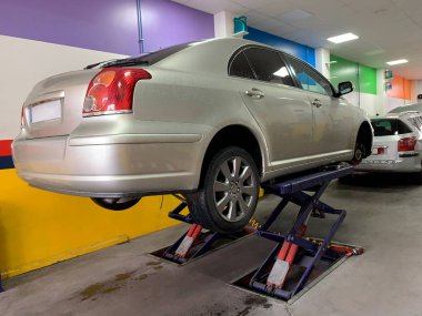 bir araba tamir dükkanında bir asansör üzerinde yükseltilmiş bir araba görünümü, yakın çekim