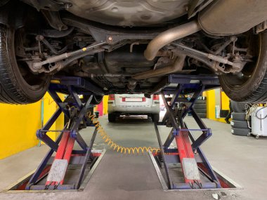 bir araba tamir dükkanında bir asansör üzerinde yükseltilmiş bir araba görünümü, yakın çekim