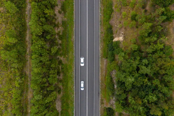 Vista aérea de cima de uma estrada rural através de uma floresta verde — Fotografia de Stock