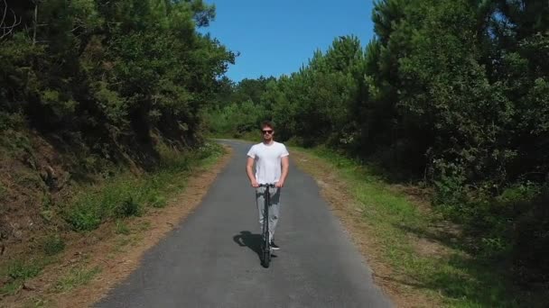 Jonge Man Rijden Een Elektrische Scooter Een Weg Het Bos — Stockvideo