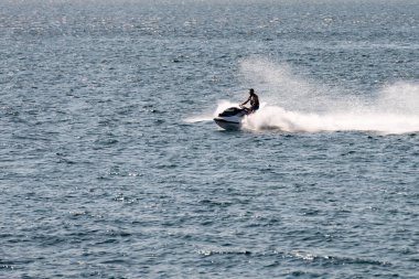 Gün batımında jet ski süren bir adam.