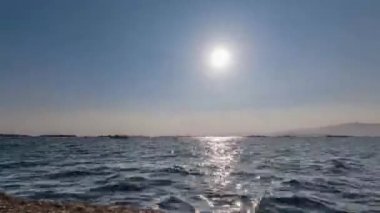 Güneş okyanusun üzerinde batıyor, açık mavi gökyüzü, parlak güneşli gün, zaman akıp gidiyor.