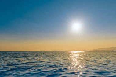 Okyanusun üzerinde güzel bir gün batımı, doğal manzara, suda güneş ışığının yansıması.