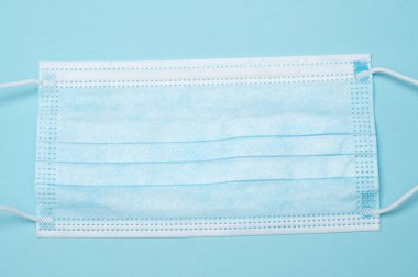 Mavi arka planda mavi tıbbi maskenin üst görüntüsü. Sağlık, güvenlik, koruma ve tıbbi tasarım, stok resimleri ve sağlıkla ilgili projeler için ideal.