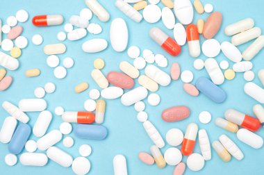 Mavi arka planda çeşitli haplar var. Sağlık hizmetleri, eczane, sağlık, sağlık ve ilaç stoku resimleri veya sağlıkla ilgili projeler için ideal.