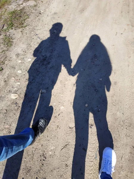 Silhouette of a couple love in casting hand in hand love on a long shadow on street.Shadows of walking pedestrians projected on the sidewalk.Artistic photo in black and white,B&W on sunny day