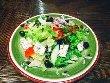 Ahşap bir masada büyük tabakta Yunan salatası