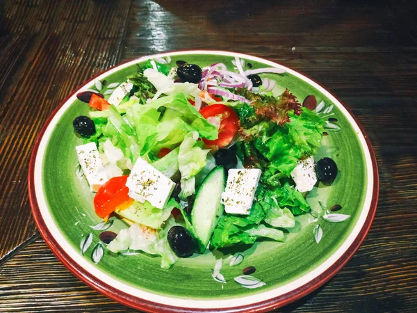 Ελληνική σαλάτα σε μεγάλο πιάτο σε ξύλινο τραπέζι — Φωτογραφία Αρχείου