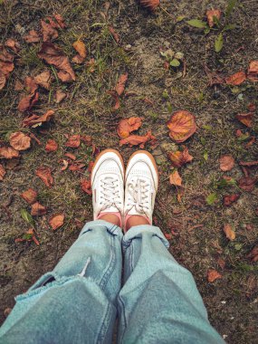 Kadın beyaz spor ayakkabıları yerde duruyor, sarı kaplı 