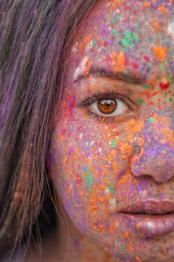 Boyalı genç Hintli yüzler. Geleneksel Hint elbiseli bir kadın Holi 'yi renk festivaliyle kutluyor. Kafasında fular olan siyah saçlı bir kız. Kahverengi gözlü doğulu kızlar.