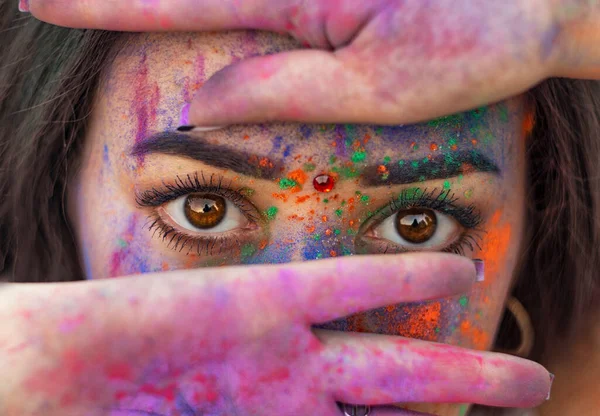Boyalı genç Hintli yüzler. Geleneksel Hint elbiseli bir kadın Holi 'yi renk festivaliyle kutluyor. Kafasında fular olan siyah saçlı bir kız. Kahverengi gözlü doğulu kızlar.