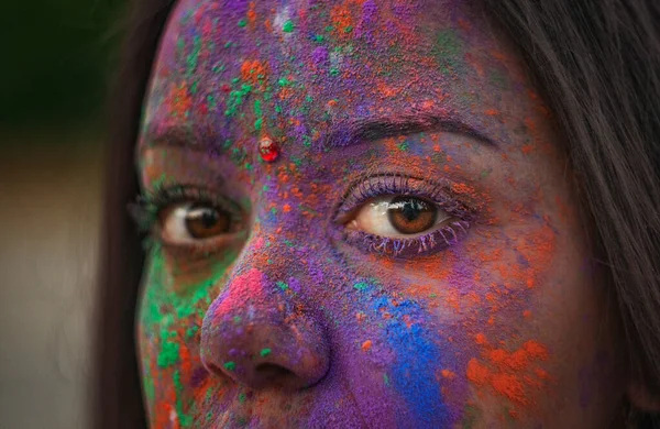 年轻的印度人脸上涂满了油漆 一位穿着传统印第安服装的妇女在彩色节庆祝霍利节 一个头上戴围巾的黑头发女孩东方女孩的褐色眼睛 图库图片