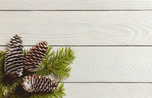 Fondo bianco di Natale in legno con rami e coni di abete, vista dall'alto, copyspace . — Foto Stock