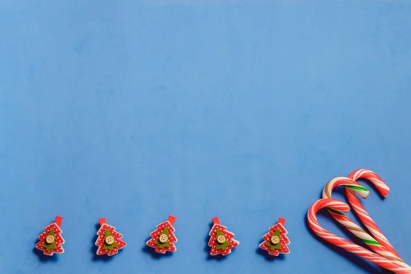 Vue du dessus trois cannes à bonbons et cinq pins en forme de sapin rouge sur fond bleu — Photo