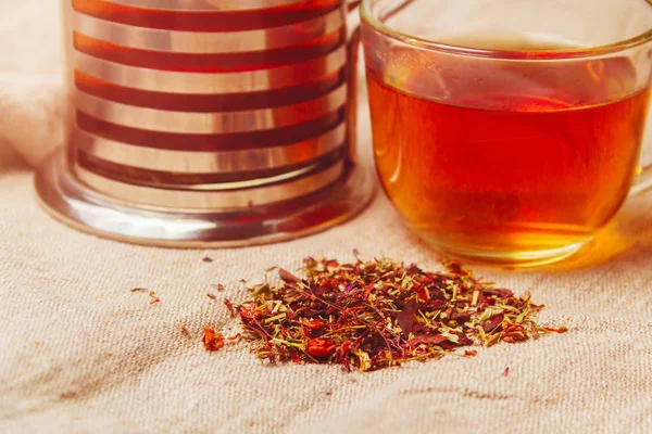 Tazza di tè nero caldo, foglie di tè essiccate su uno sfondo di sacco leggero — Foto Stock