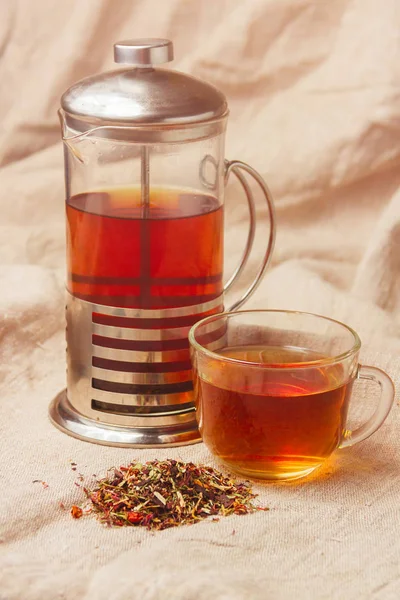 Taza de té negro caliente, hojas de té secas sobre un fondo de saco claro — Foto de Stock