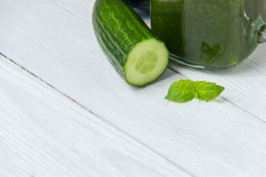 Beyaz ahşap zemin üzerinde malzemelerle sağlıklı yeşil smoothie