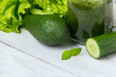 Beyaz ahşap zemin üzerinde malzemelerle sağlıklı yeşil smoothie