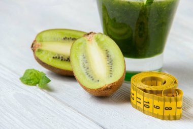 Beyaz ahşap zemin üzerinde malzemelerle sağlıklı yeşil smoothie