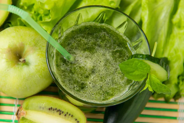 Healthy green smoothie with ingredients on wooden background