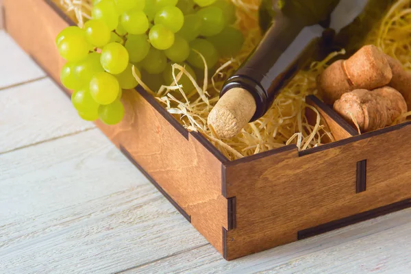 Fles wijn, kurken, druiven in houten kist. — Stockfoto