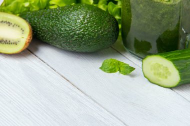 Beyaz ahşap zemin üzerinde malzemelerle sağlıklı yeşil smoothie