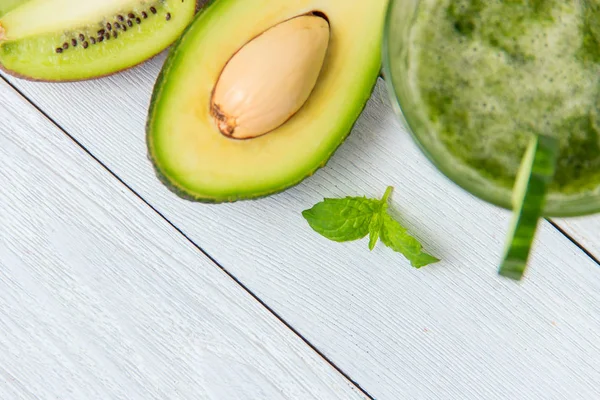 Gesunder grüner Smoothie mit Zutaten auf weißem Holzgrund — Stockfoto