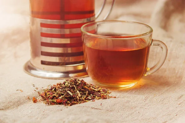 Tazza di tè nero caldo, foglie di tè essiccate su uno sfondo di sacco leggero — Foto Stock