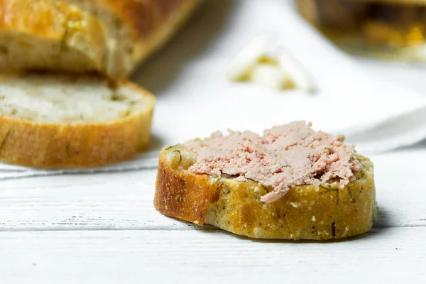 stock image Garlic baguette with pate on white kitchen towel on wooden table.