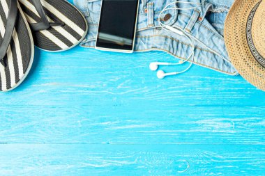 Çerçeve şık şapka terlik kot smartphone kulaklık boşaltmak için metin, mavi ahşap arka plan üzerinde tatil yaz.