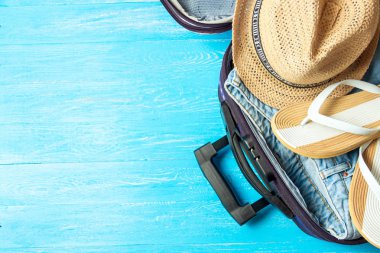 Açık bavul seyahat aksesuarları boşaltmak mavi ahşap tablo ile.