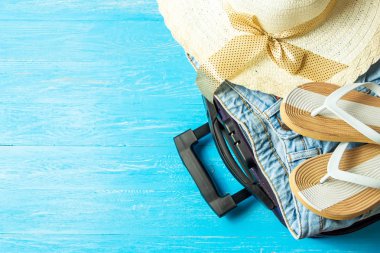 Açık bavul seyahat aksesuarları boşaltmak mavi ahşap tablo ile.