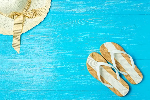 Frame elegante vrouwelijke stro hoed slippers op blauwe houten achtergrond, copyspace voor tekst, zomervakantie. — Stockfoto