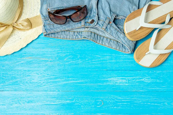 Marco elegante mujer sombrero de paja zapatillas jeans gafas de sol sobre fondo de madera azul, espacio de copia para el texto, vacaciones de verano . — Foto de Stock