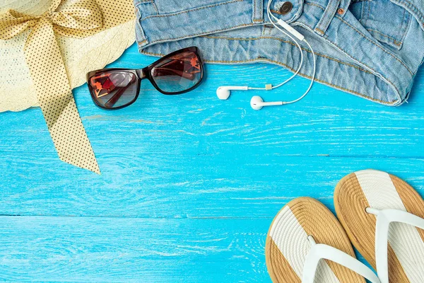 Cadre élégant chapeau de paille femme pantoufles jeans lunettes de soleil sur fond de bois bleu, copyspace pour le texte, vacances d'été . — Photo