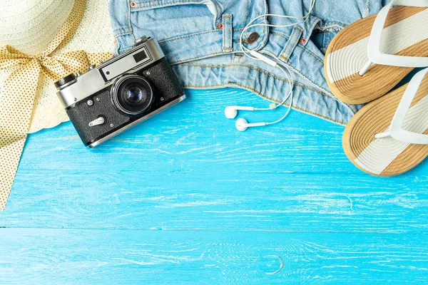 Frame elegante vrouwelijke stro hoed slippers jeans camera op blauwe houten achtergrond, copyspace voor tekst, zomervakantie. — Stockfoto
