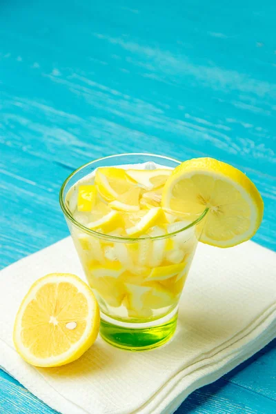 Acqua con limone. Limonata con fette di limone su fondo di legno blu . — Foto Stock