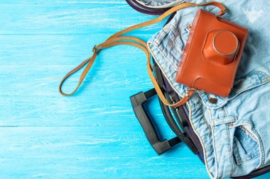 Açık bavul seyahat aksesuarları boşaltmak mavi ahşap tablo ile.