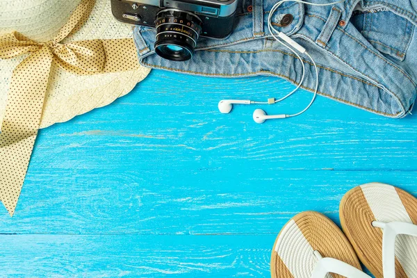 Marco elegante mujer sombrero de paja zapatillas jeans gafas de sol sobre fondo de madera azul, espacio de copia para el texto, vacaciones de verano . — Foto de Stock