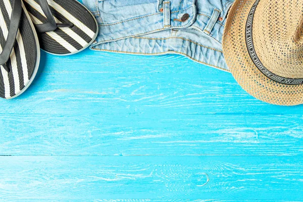 Πλαίσιο κομψό ψάθινο καπέλο παντόφλες τζιν σε μπλε φόντο ξύλινη, copyspace για το κείμενο, καλοκαιρινές διακοπές. — Φωτογραφία Αρχείου