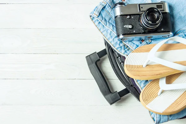 Valise ouverte avec accessoires de voyage sur table en bois blanc avec espace de copie . — Photo