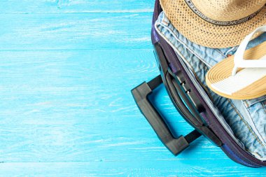 Açık bavul seyahat aksesuarları boşaltmak mavi ahşap tablo ile.