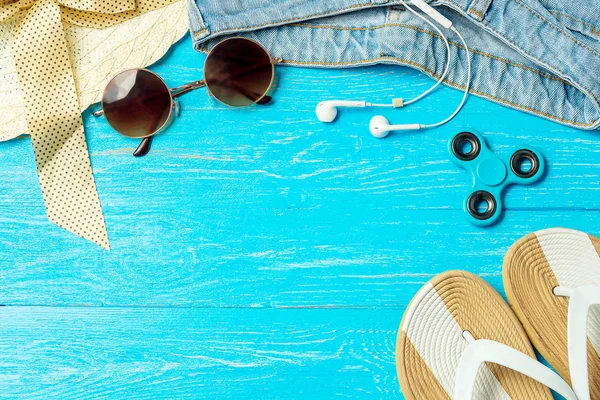 Frame elegante vrouwelijke stro hoed slippers jeans zonnebril op blauwe houten achtergrond, copyspace voor tekst, zomervakantie. — Stockfoto