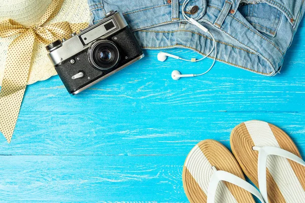 Frame elegante vrouwelijke stro hoed slippers jeans camera op blauwe houten achtergrond, copyspace voor tekst, zomervakantie. — Stockfoto