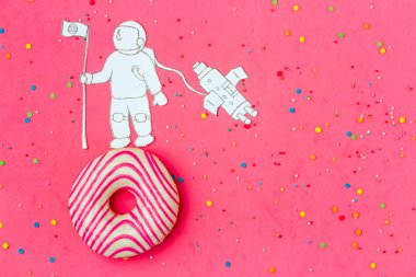 Yaratıcı yiyecekler minimalizm, astronot, uzay gemisi üstten görünüm, kopya alanı ile pembe gökyüzündeki gezegen olarak çörek.
