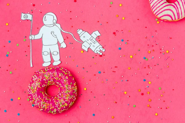 Creative Food Minimalism, Donut in Shape of Planet in Pink Sky with Astronaut, Space Ship Top View, Copy Space.